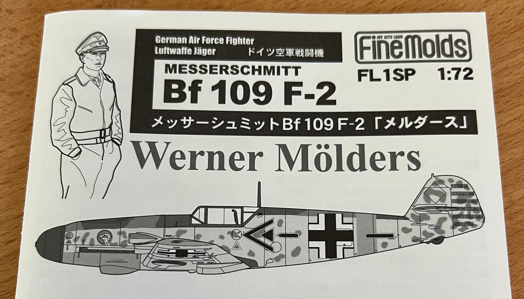 Model kit label for Messerschmitt Bf 109 F-2 with a pilot figure and camouflage airplane illustration.