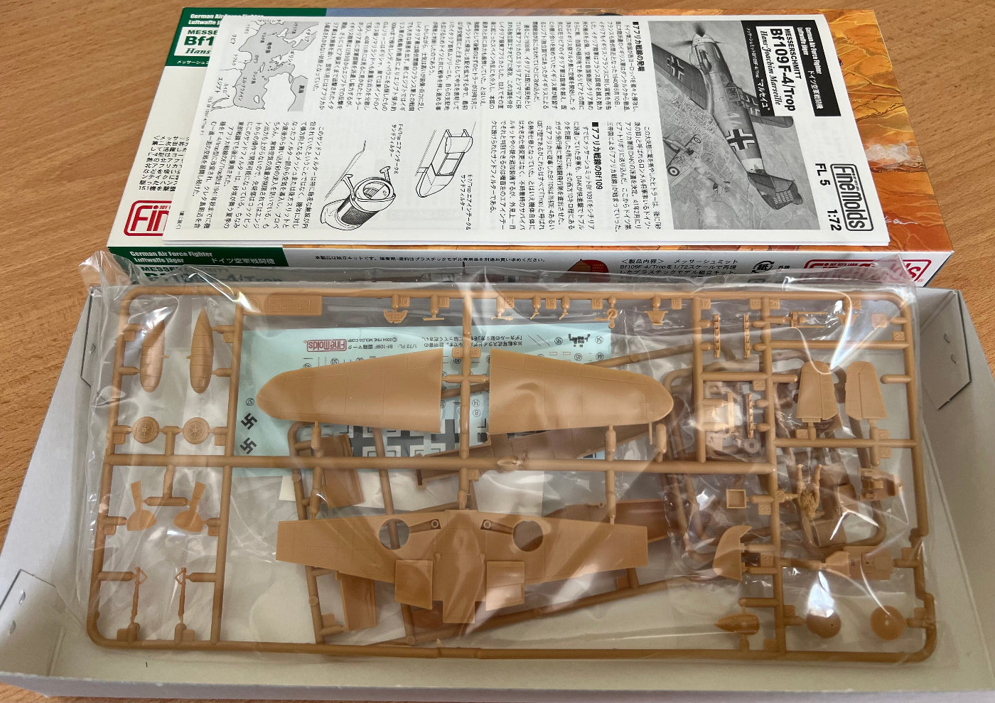 Model airplane kit with parts and packaging on a wooden surface