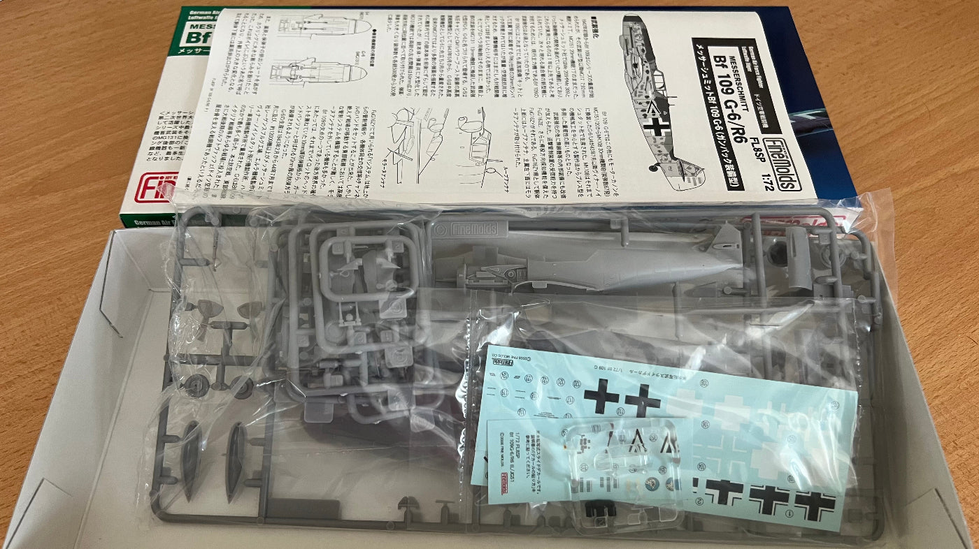 Model kit packaging with clear plastic parts and printed instructions on a wooden surface