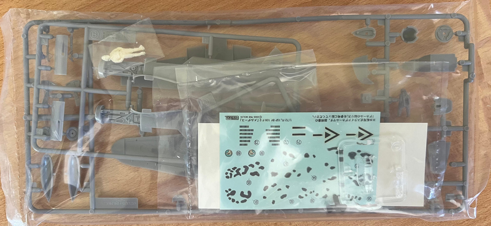 Model kit packaging with clear parts and labels on a wooden surface