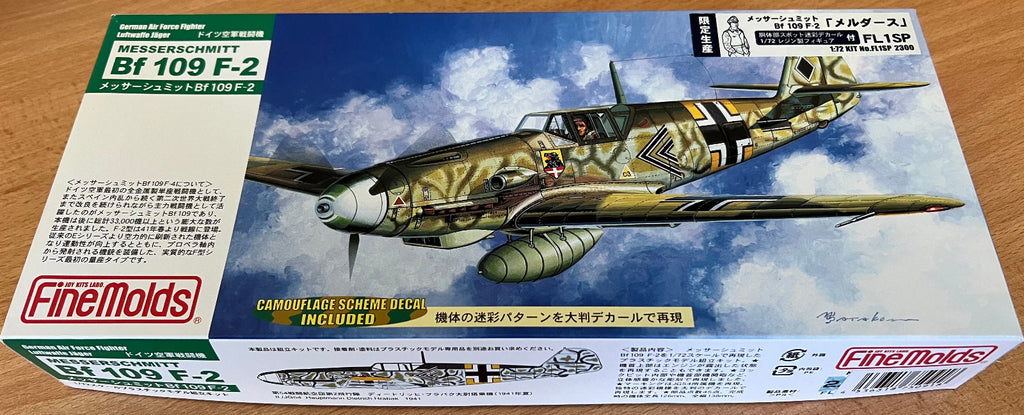 Model airplane box with camouflage design and 'FineMolds' branding on a wooden surface.