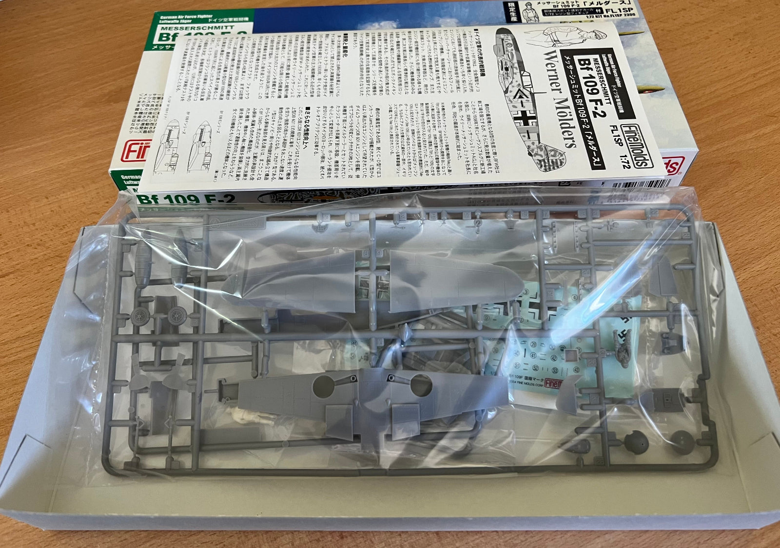 Model kit packaging with clear plastic parts on a wooden surface