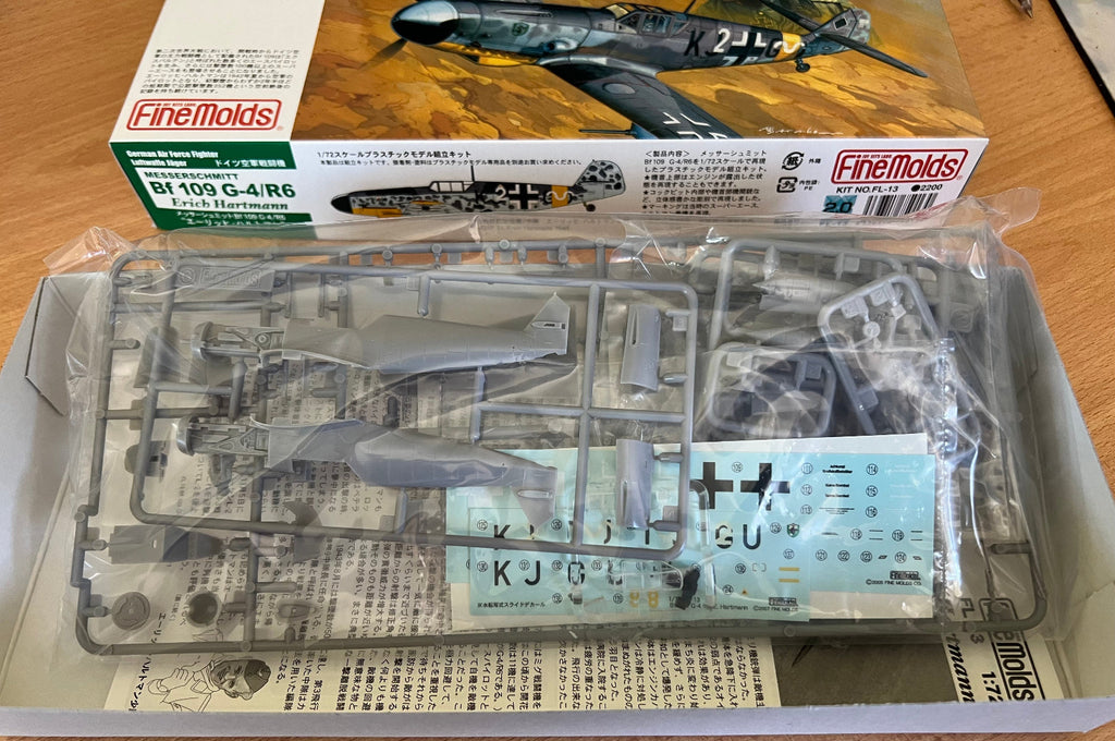 Model airplane kit with clear parts and printed components on a wooden surface.