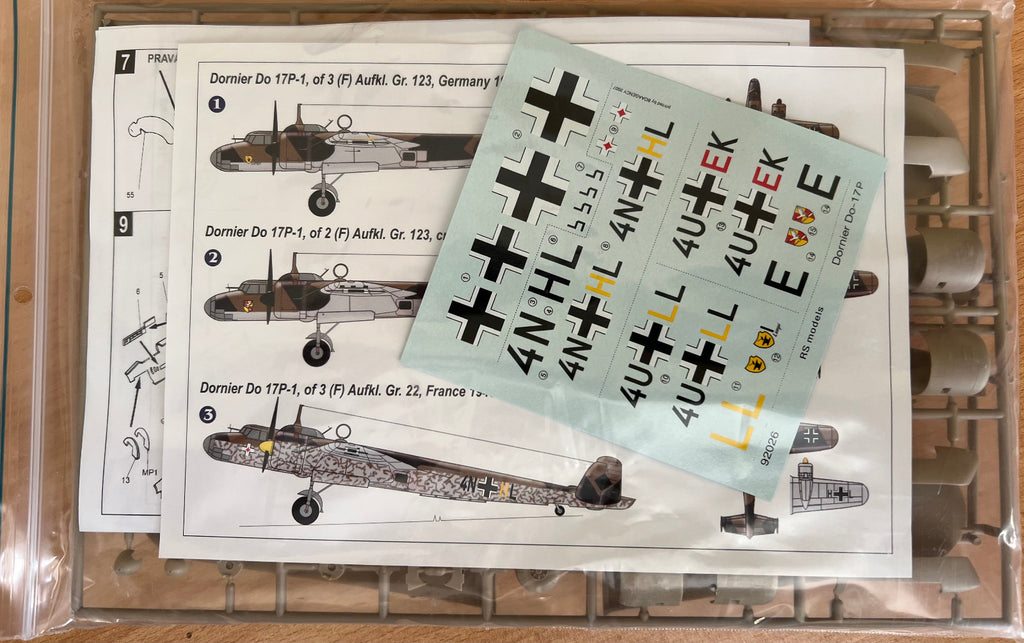 Model airplane decals with a sheet of cross-shaped markers on a plastic model kit background.